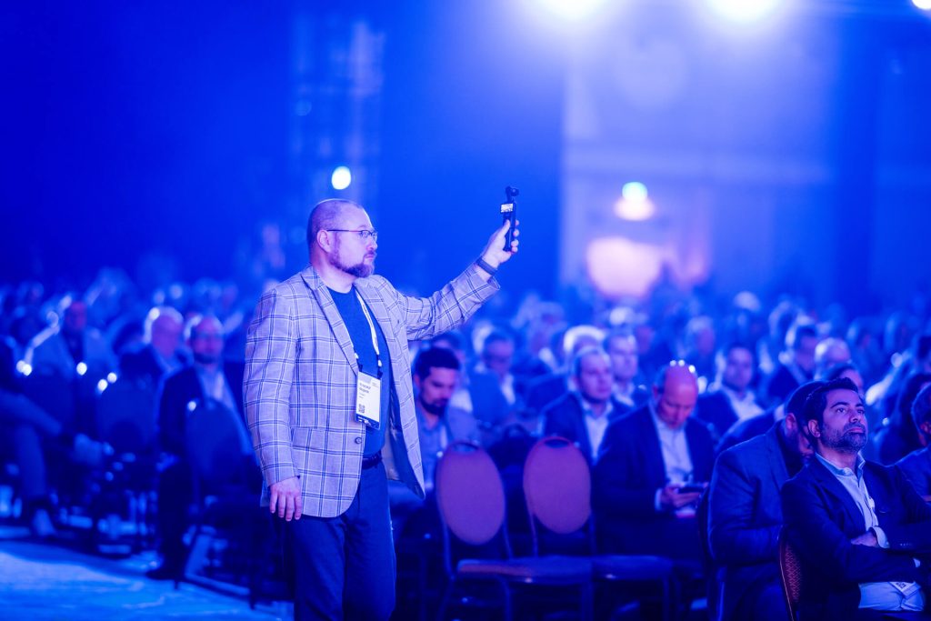 Man filming with phone during conference
