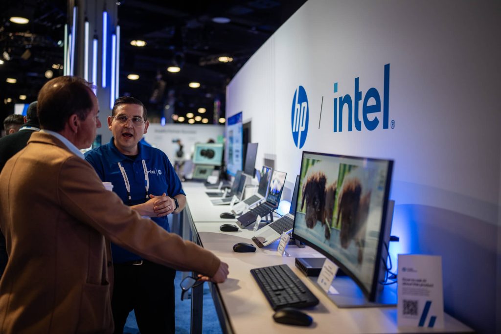 Man in blue shirt talks to attendee at hp intel booth