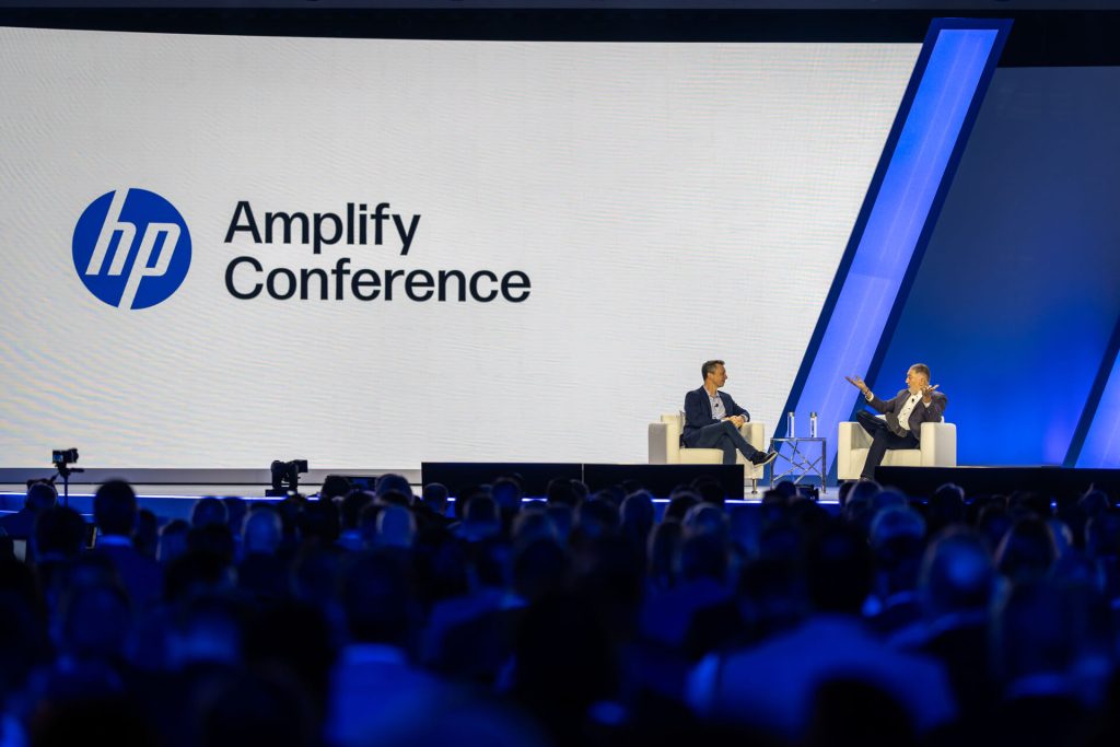 Two men in chairs talking on stage at hp amplify conference